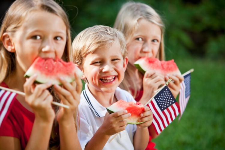 Children eating watermelon, holding American flags. Focus on boy, 4 years.